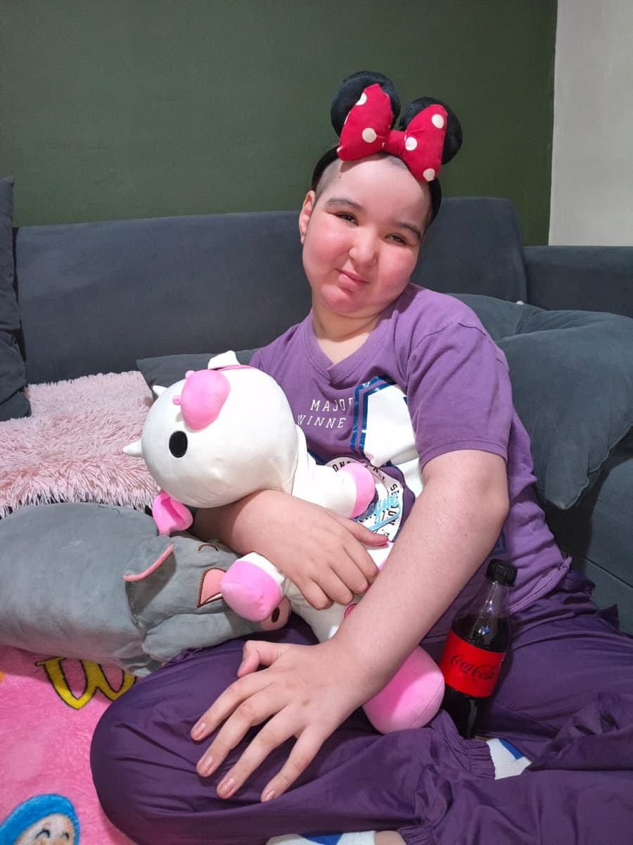 Manu con orejas de Minnie, abrazando a su vaquita de peluche